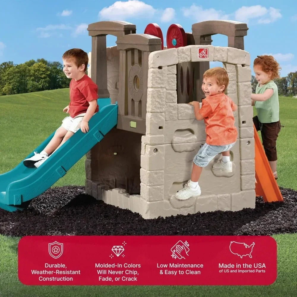 Three young children play on the Woodland Climber II Kids Playset for Ages 2 to 6 Years, which features a toddler slide and climbing steps, set on mulch in a grassy area under a bright blue sky.