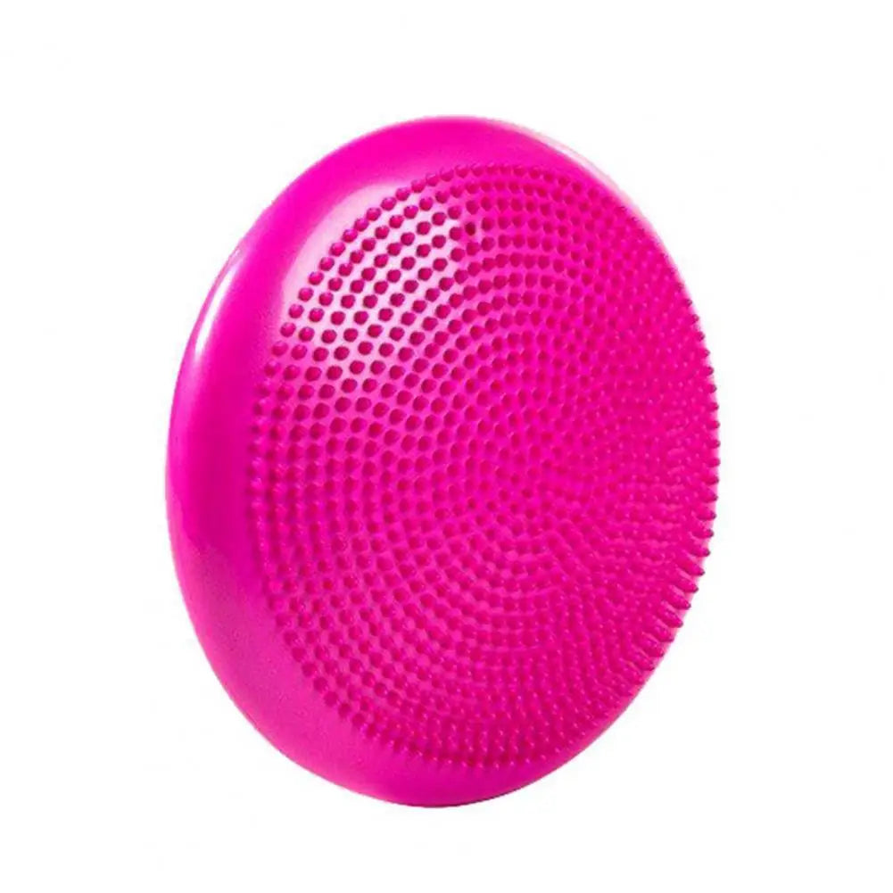 A bright pink silicone facial cleansing brush resembling a balance disc with textured bristles and smooth edges, designed to enhance core strength during skincare routines.