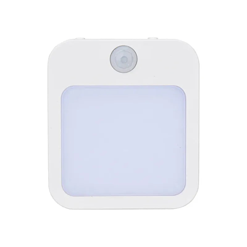 The Dimmable Motion Sensor LED Night Light features a square, white body with a rounded sensor at the top and a larger rectangular panel. It boasts modern aesthetics and energy efficiency, posed elegantly against a plain white backdrop.