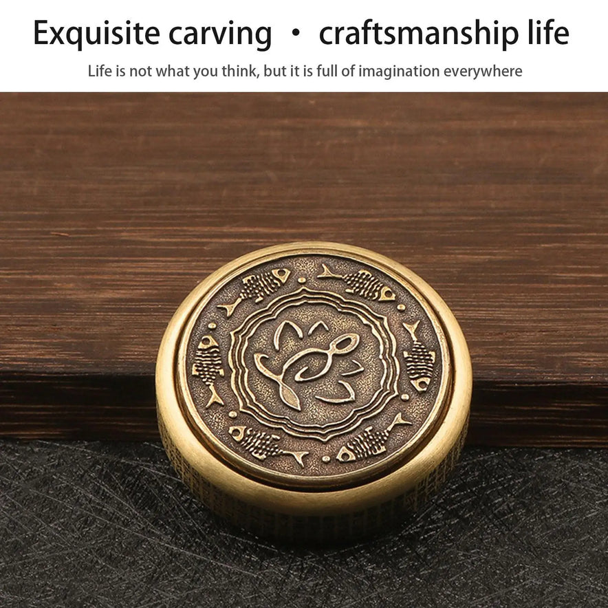 The Zen Buddha Fidget Spinner Metal EDC Fidget Toy for Adults, featuring intricate bronze carvings of a central fish and smaller fish, rests on a dark wooden surface. Text above reads “Exquisite carving • craftsmanship life.”.