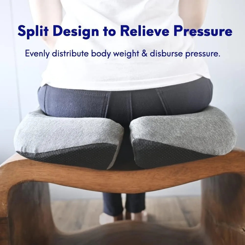 A person sits on a wooden chair with a Cushion Lab Patented Pressure Relief Seat Cushion, featuring a gray split, 100% cotton cushion designed to relieve pressure and evenly distribute body weight. Blue text reads, Split Design to Relieve Pressure - Evenly distribute body weight & disburse pressure.