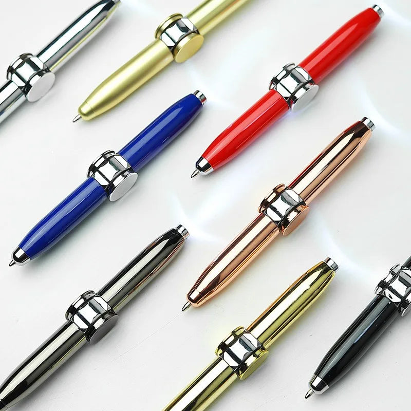 Four rechargeable metal fidget pens with LED and spinner in assorted colors are arranged diagonally on a light surface. Each multi-functional pen features premium material, a unique chrome central ring, and trim for office or travel use.