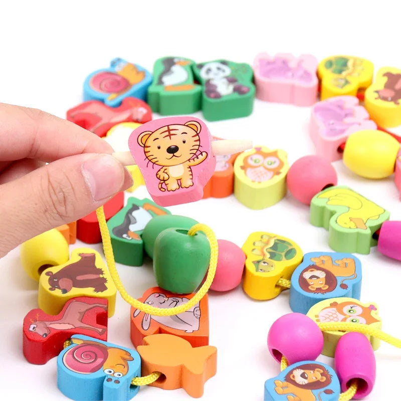 A close-up of New 50pcs/Lot Baby Wooden Lacing Beads shows animal illustrations, perfect for educational play. A hand holds a tiger bead on a yellow string. Featuring various animals like owls, pandas, and snails, these colorful beads enhance fine motor skills in preschoolers.