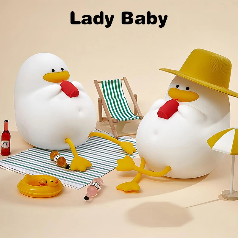 Two cartoonish, egg-shaped characters with yellow beaks and feet relax under Lady Baby text. One has a hat; both hold red bottles. A striped chair, small umbrella, and drinks on a mat are illuminated by the Cute Cartoon Duck Rechargeable LED Night Light—a charming bedside lamp for kids.