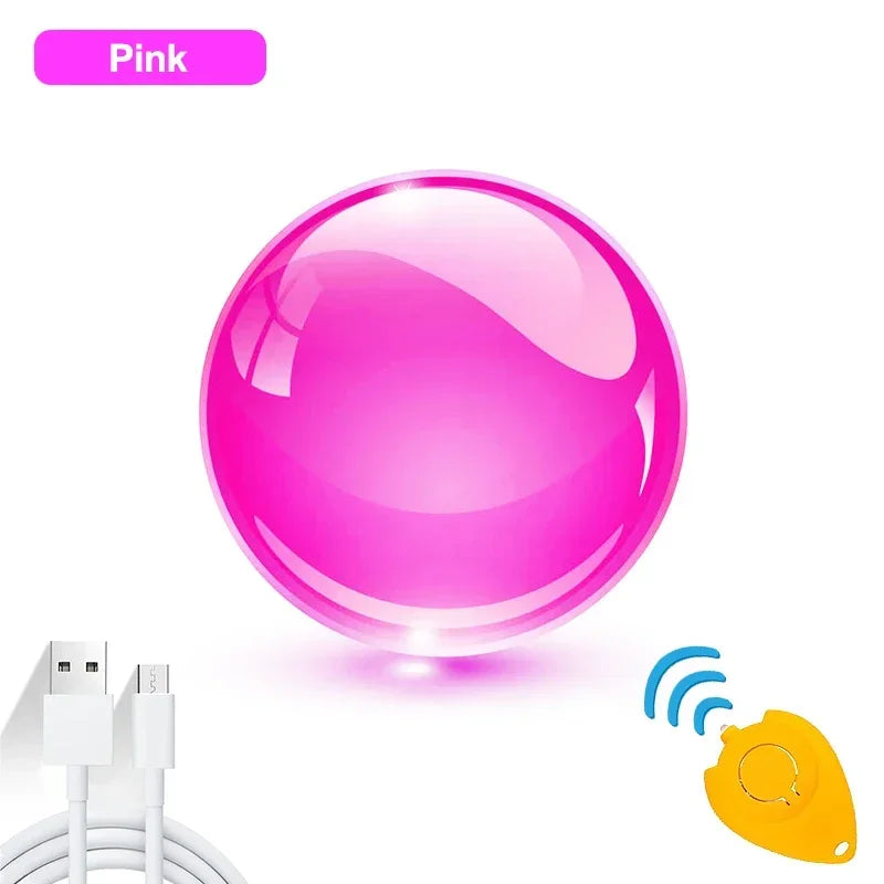 The pink Magic Flying Ball Mini Toy with automatic obstacle avoidance is displayed with a white USB charging cable and a yellow remote control emitting wireless signals.