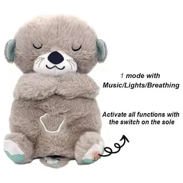 A plush grey otter with closed eyes and a nose, featuring a heart on its chest. The Musical Breathing Otter Plush Toy for Newborn Comfort reads: 1 mode with Music/Lights/Breathing and Activate all functions with the switch on the sole. Ideal for newborn sensory play.