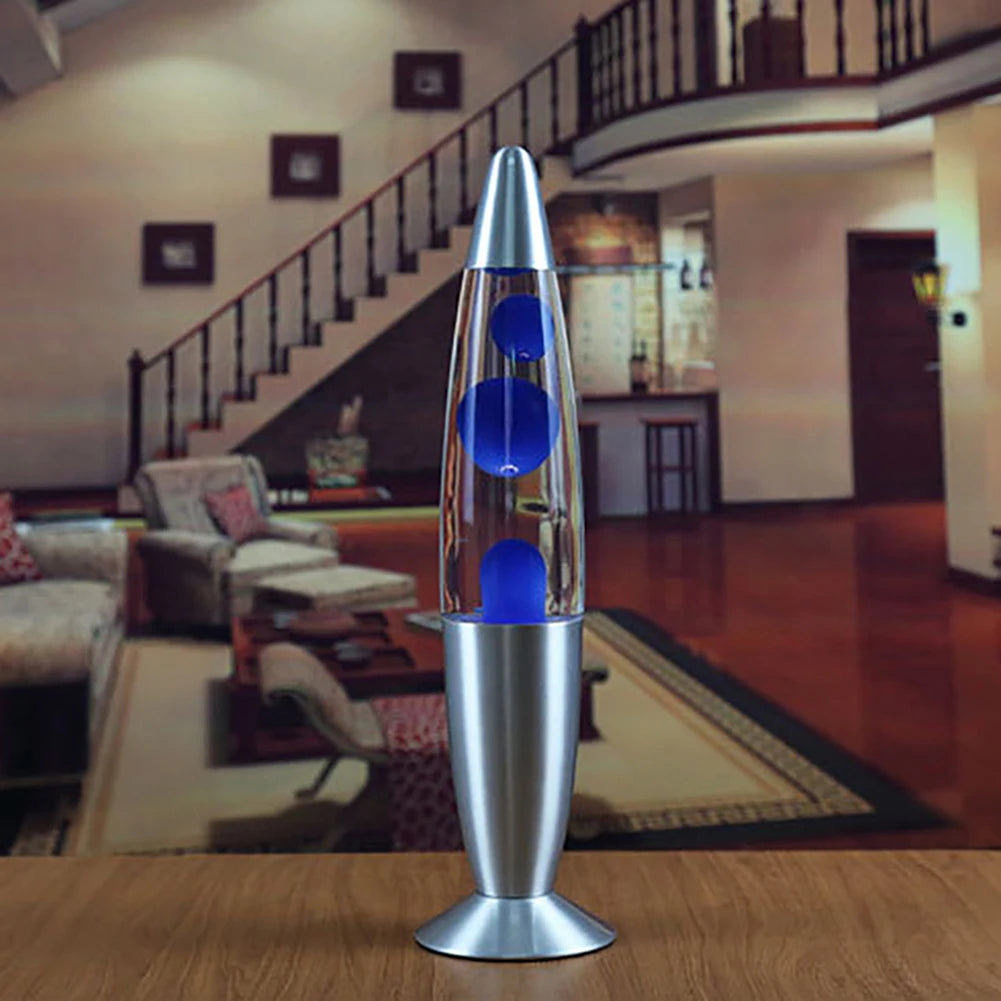 A Luminous Volcano Jellyfish LED Night Light adds a relaxing ambiance on a wooden table, featuring blue blobs and gentle lava motion. Its silver base and top complement the living rooms spacious hardwood floors, stairs, and furniture.