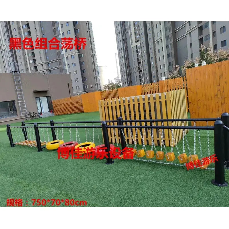 Playground equipment on green artificial turf features a metal toy balance beam, climbing nets, and stepping stones for unisex children aged 3-8. Its in front of a wooden fenced area with tall residential buildings in the background. Chinese text is visible.