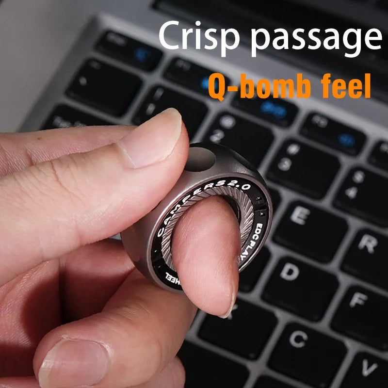 A hand holds a Spystar Mechanic Ring Fidget Spinner Fingertip Gyro above a laptop keyboard. Text over the image reads Crisp passage and Q-bomb feel, showcasing this unique magnetic metal adult anti-stress toy.