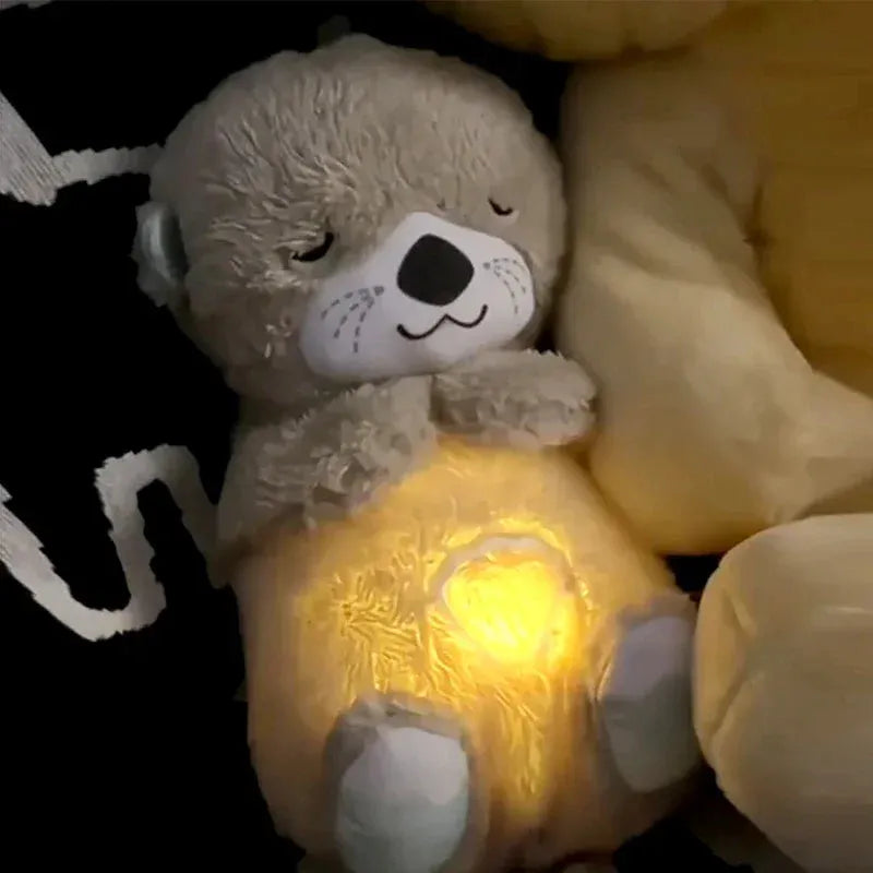 A Soothing Otter Musical Plush Toy for newborns lies on a dark surface, its closed eyes and glowing heart-shaped light creating a cozy sensory experience that comforts and charms everyone who sees it.