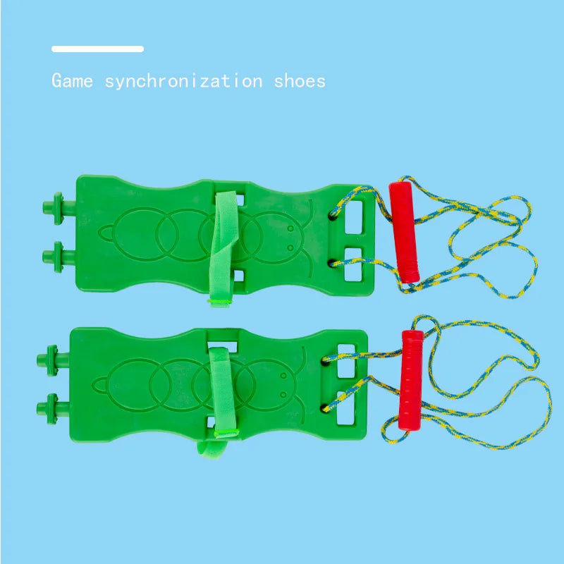 Two green plastic toy flip-flop-shaped shoes with yellow and green ropes and red handles rest on a blue background. Text reads Game synchronization shoes. These Interactive Outdoor Balance Board Seesaws for Kids are perfect sensory training toys to enhance balance skills while enjoying outdoor play.