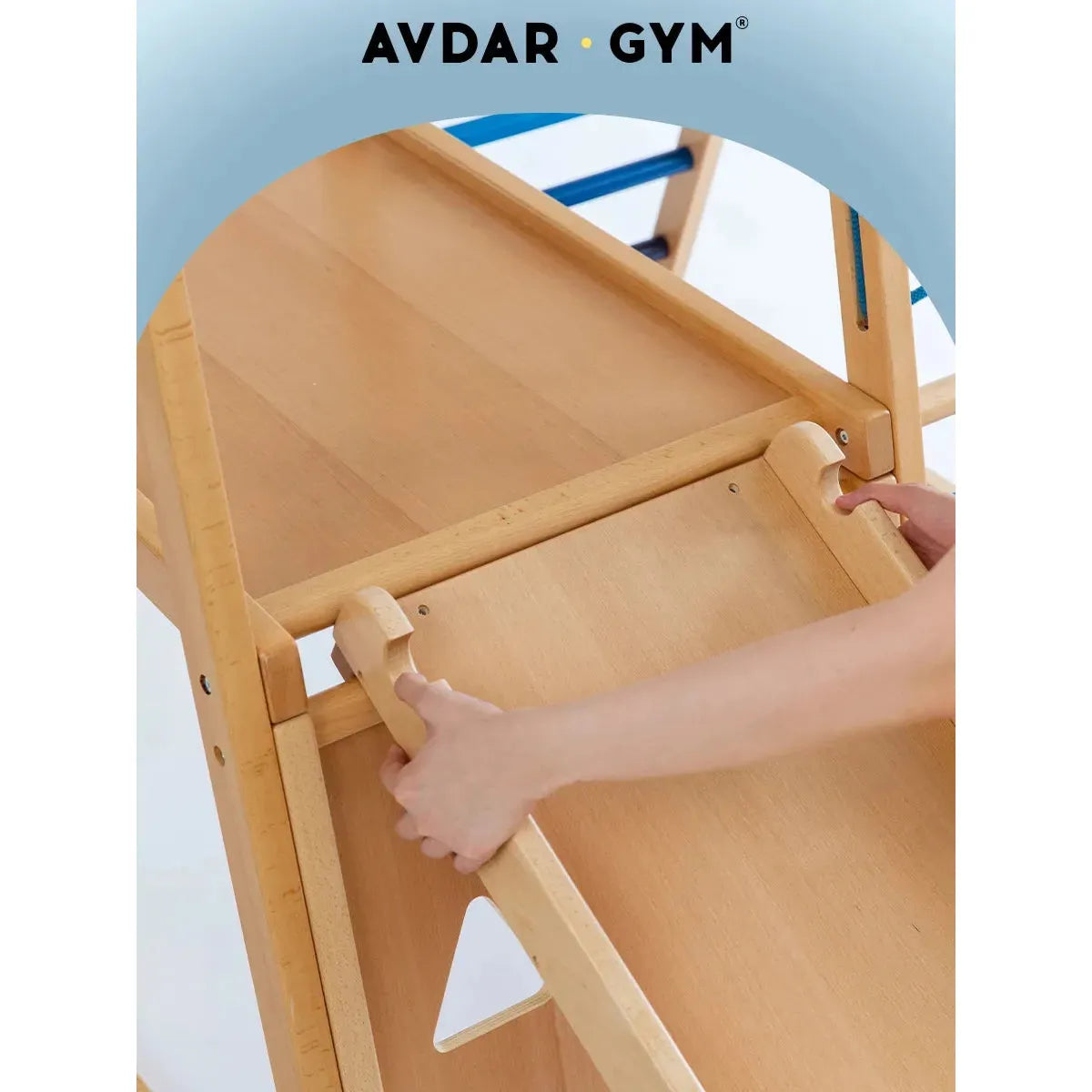 Someone modifies an Indoor Adventure Climbing Frame, ideal for a home playground. The setup, akin to a Sunny Day Climbing Frame, includes smooth wooden surfaces and blue details. AVDAR GYM is emblazoned at the top on a light blue backdrop.