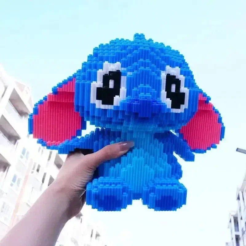 A hand holds up the Large Stitch Building Block Assembly Toy, a 30cm blue 3D DIY puzzle with big pink ears and eyes, resembling Stitch, against a clear sky and tall buildings.