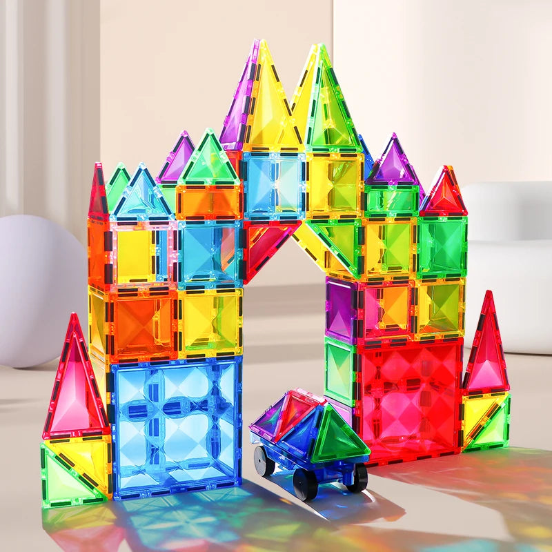 Using the Montessori Magnetic Building Blocks Set, a colorful castle-like structure with an arch is formed. A small vehicle of the same educational blocks is parked underneath. The translucent tiles feature vibrant red, blue, green, yellow, and purple hues.