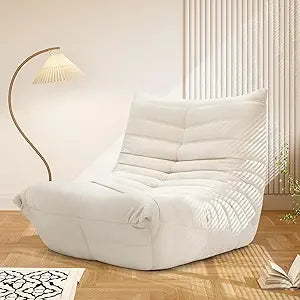 A modern, white Fireside Chair Bean Bag for adults sits on a wooden floor near a curved floor lamp. Sunlight streams through vertical blinds, casting shadows across the minimalistic, cozy room.