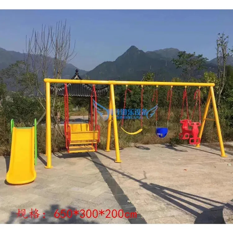 A purple playground set with outdoor toys, including climbing nets, swinging bridges, and multiple unisex swings like a yellow hoop, blue bucket seat, and red horse-shaped swing. The scene is beautifully framed by mountains and trees under a clear sky.