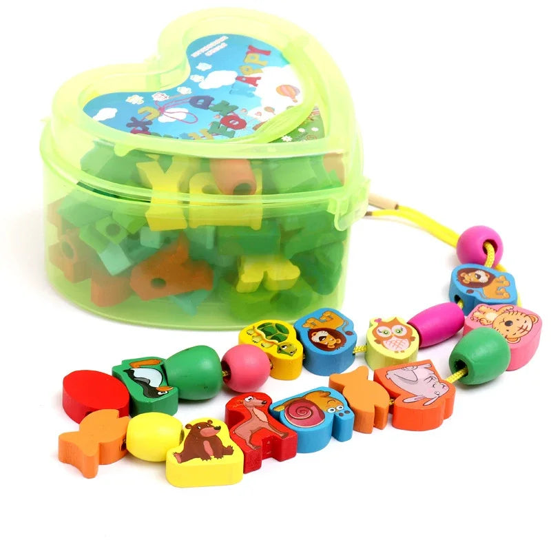 A heart-shaped clear box houses colorful alphabet and animal beads for kids. Ideal for educational play, it boosts fine motor skills. In front, a string with baby wooden lacing beads in animal shapes is neatly arranged on a white surface.