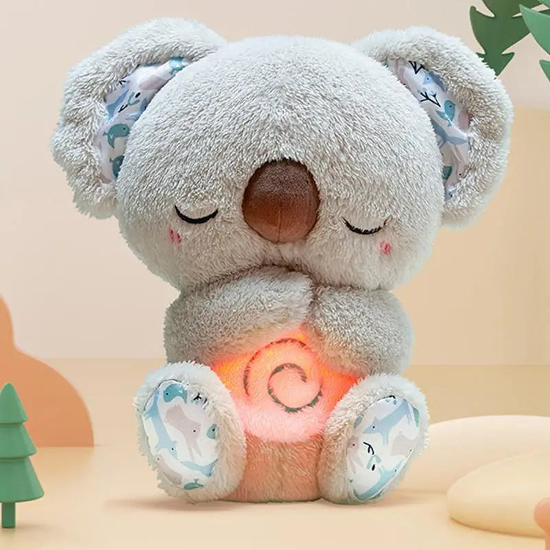 The Koala Night Light Plush Toy: Musical Sensory Sleep Aid for Newborns features a serene plush koala with closed eyes and blushing cheeks, its glowing belly resembling a soft night light. Patterned inner ears add charm, while it creates a peaceful ambiance ideal for enjoying soothing melodies.