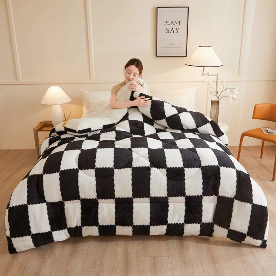 A person sits on a bed with the KDJEIKZ Ultra Cozy Winter Weighted Blanket, its milk velvet texture adding a cozy touch. The bedroom features beige walls, two lamps, a brown chair, and a small framed quote. Light wood floors complete the rooms serene ambiance.