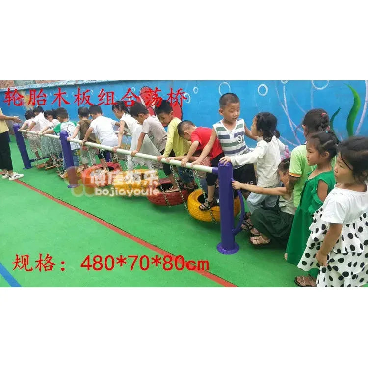 Children aged 3-8 enjoy an indoor adventure on the unisex swinging bridges, gripping metal bars for balance. The floor has green mats that complement the blue wall with playful illustrations. Part of the outdoor toys collection, it includes childrens swings and climbing nets for sensory integration and physical training.