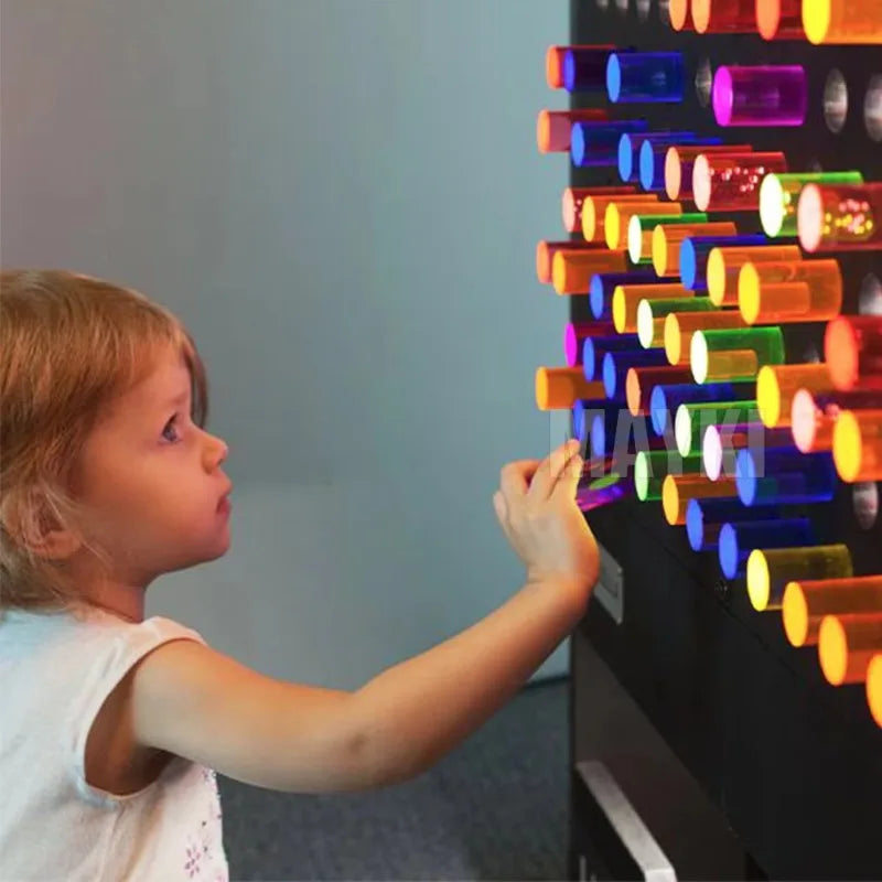 A young child engages with the High Quality Snoezelen Sensory Room Toy Light LED Acrylic Peg Board Interactive Sensory Wall Panel for Kids with Autism, placing glowing pegs to form vibrant, illuminated patterns—ideal for sensory rooms or walls.
