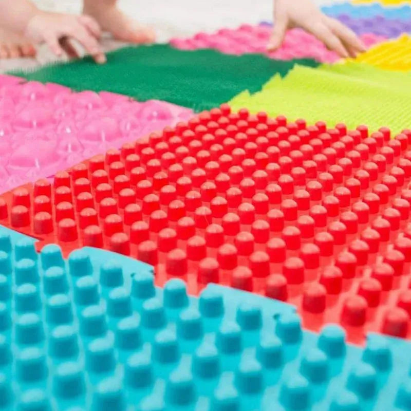 A close-up of the vibrant Montessori Sensory Integration Training Balance Stones shows children’s hands reaching out for tactile play. Featuring red, pink, green, and yellow patterns, it encourages sensory exploration through touch and is perfect for early learning and coordination.