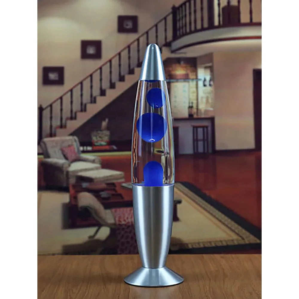 The Luminous Volcano Lava Jellyfish LED Night Light, with its creative 25W design, enhances a rooms ambiance beautifully. This silver and blue lamp features mesmerizing bubbles that create a relaxing atmosphere in a cozy living area with wooden floors, a staircase, sofas, and wall decor.