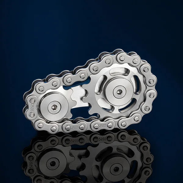 The Bike Chain Metal Fidget Spinner with Magnetic Slider, a 9 Gear Linkage Stress Relief Toy for Adults, rests on a reflective surface against a dark blue background. Its intricate chains and gears are highlighted in the centered composition, offering mesmerizing stress relief.