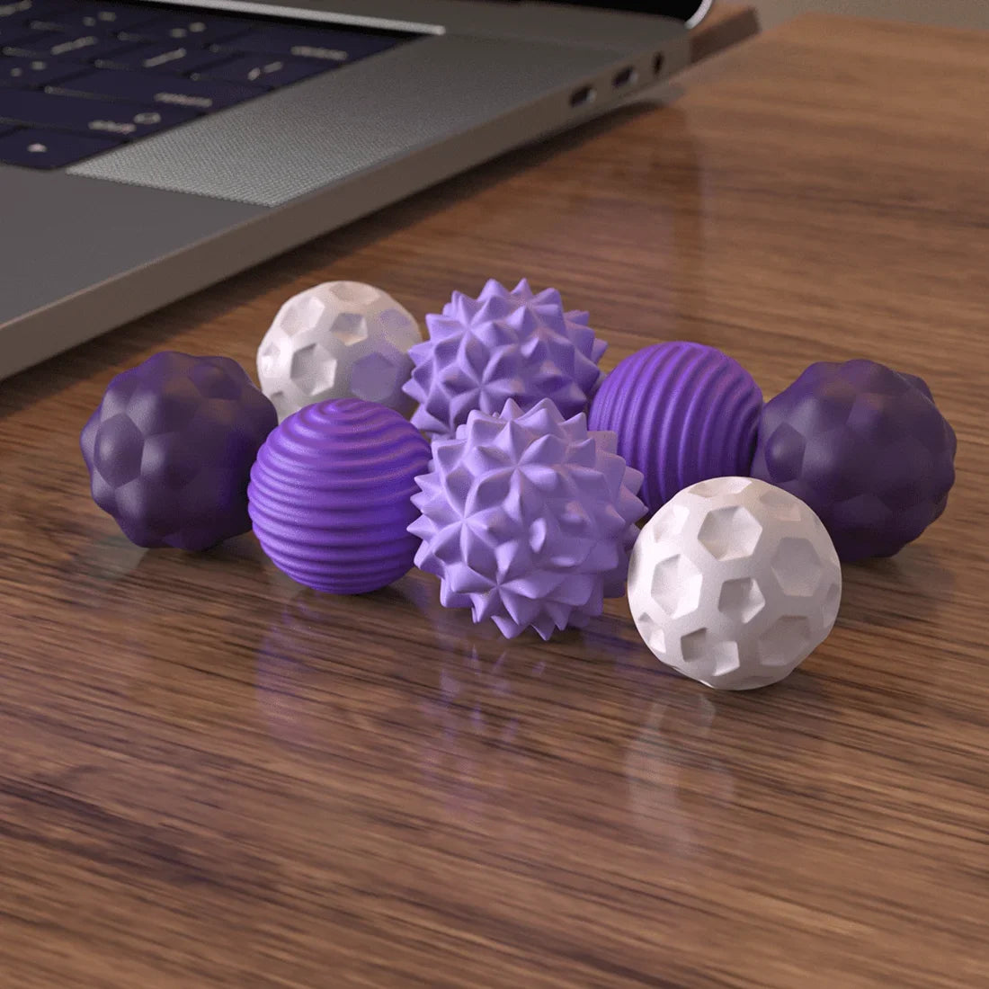 A 4Pcs 8PCS Silicone Magnetic Balls Set for Adults to Calm Restless Hands and Anxious Mind in purple and white is arranged on a wooden table next to a laptop keyboard.