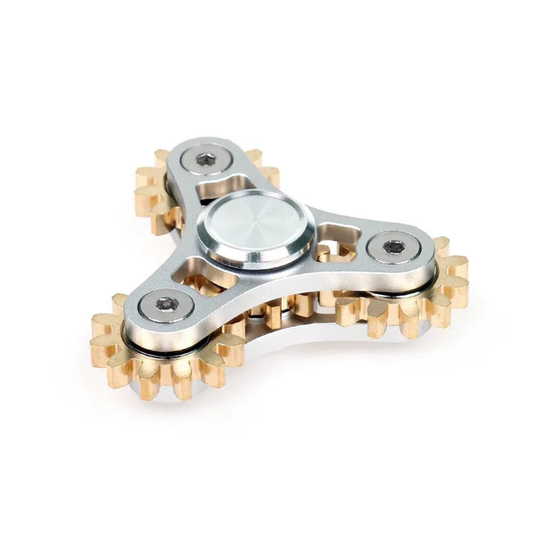 A close-up image showcases the Bike Chain Metal Fidget Spinner with a tri-spoke design. The silver main body has circular accents, and each arm ends in a gear-like gold tip, providing stress relief and an industrial look, set against a plain white background.