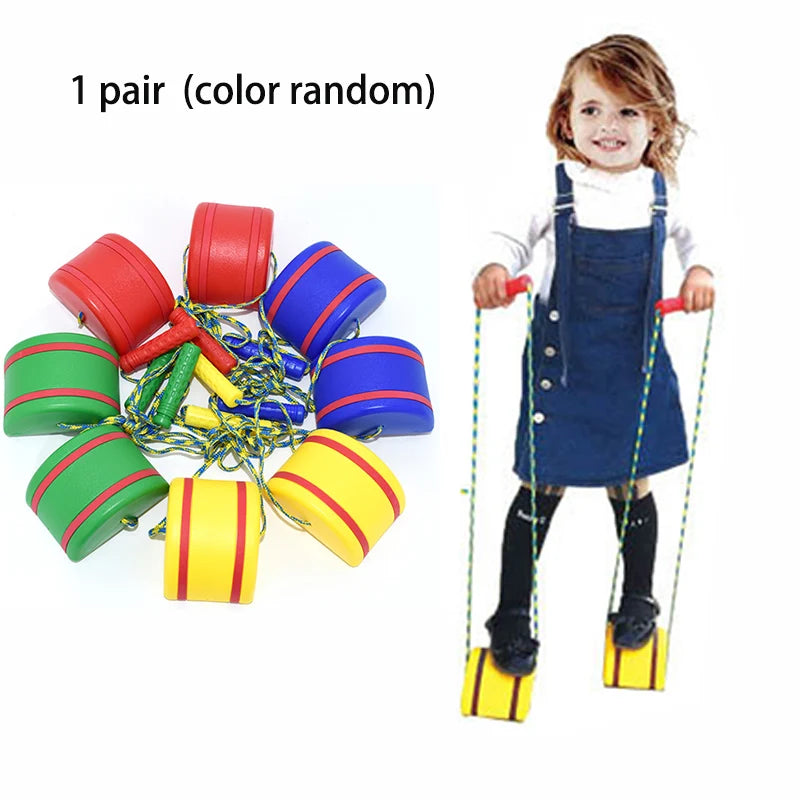 A child in a denim dress and striped shirt expertly balances on bucket stilts, ideal for sensory training. Six pairs of colorful stilts in red, blue, green, and yellow are nearby. Text reads 1 pair (color random). Its perfect for outdoor adventures with the Interactive Outdoor Balance Board Seesaw.