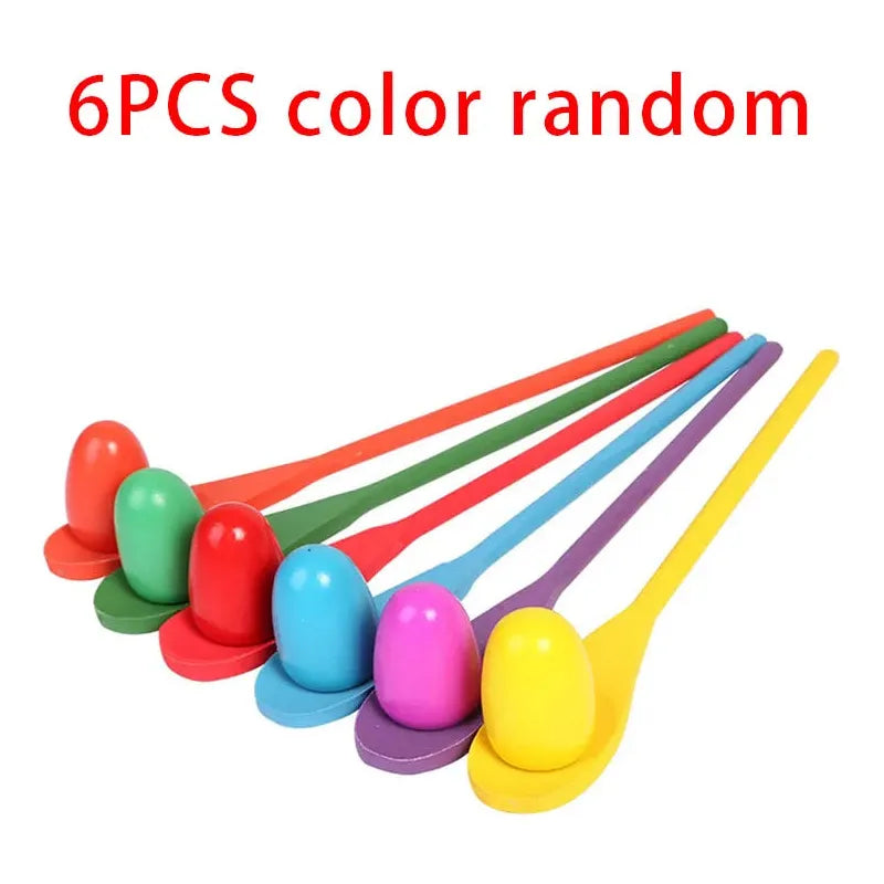 A set of six vibrant plastic spoons, each holding a matching egg-shaped object in red, green, blue, purple, pink, and yellow for skill development. The 6-Piece Parent-Child Sensory Balance Game offers fun outdoor play and effective sensory training. Text above says 6PCS color random.