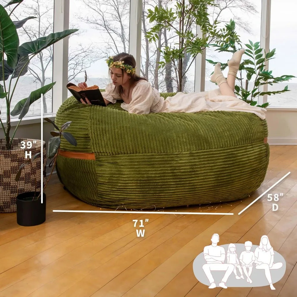 A woman in a light dress and flower crown reads on a Fuf XXL Foam Filled Bean Bag Chair, Moss Green, 6 Feet, lounging in a sunlit room with plants and large windows. (Dimensions: 71W x 58D x 39H.).