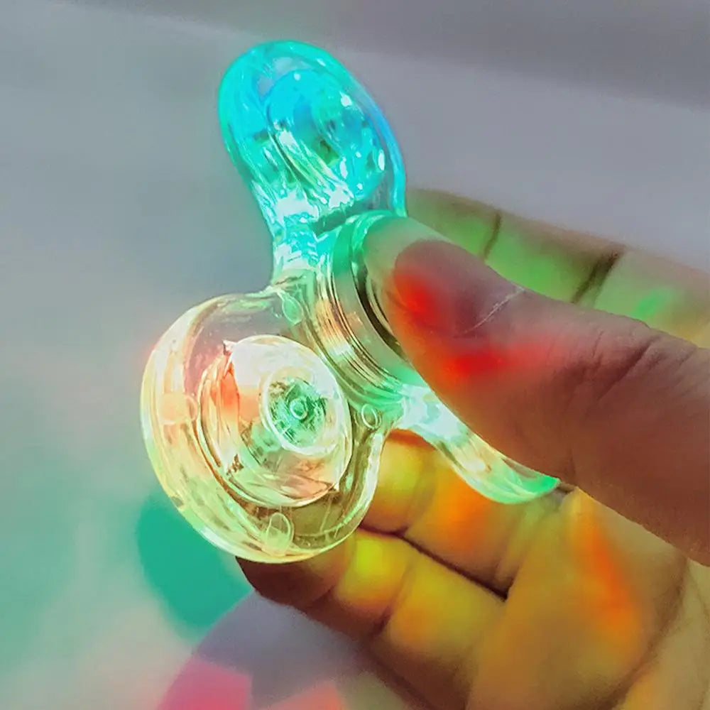 A hand holds a Crystal Finger Spinner Luminous LED Light Fidget Spinner, casting vibrant green, blue, and red hues on the skin to enhance stress relief.