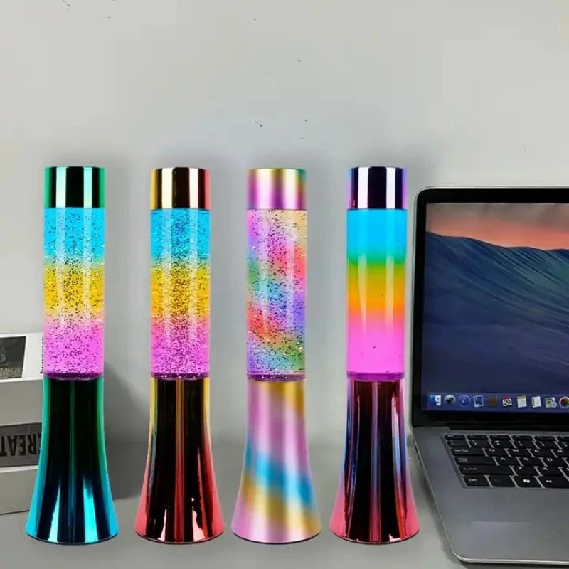 Four Color-Changing LED Glitter Lava Lamps, each 13 inches, sit next to an open laptop. The gradient designs and LED sequins transform them into vibrant, ever-changing works of art, adding a decorative touch to the scene.