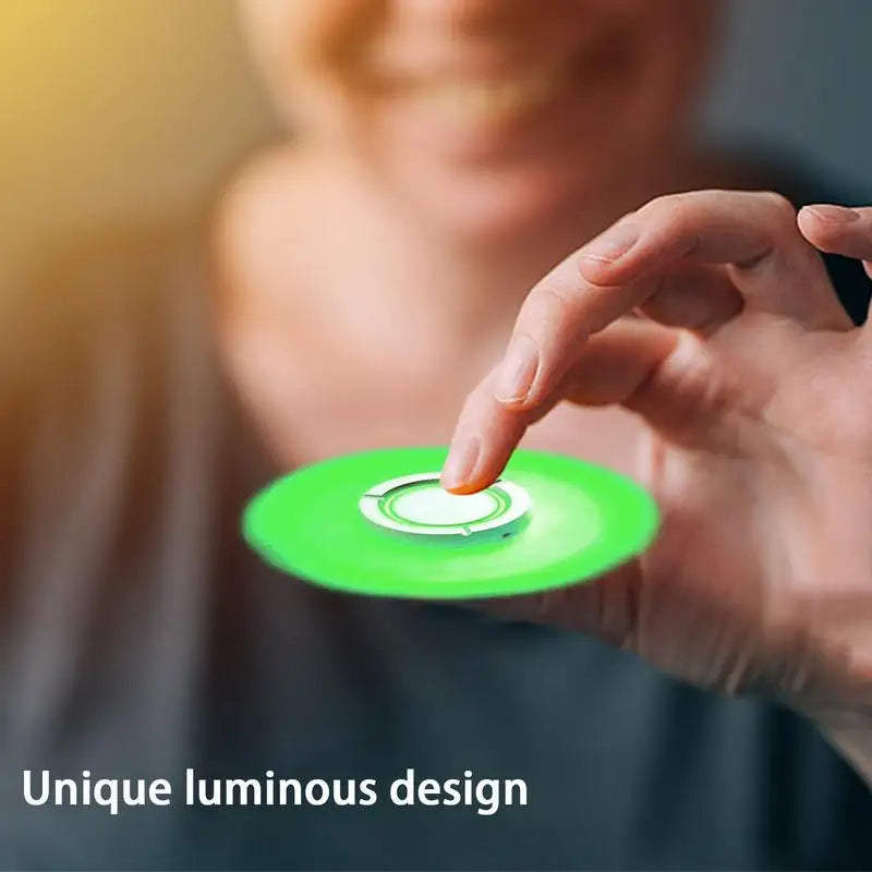 A person smiles while holding a green, glowing toy between two fingers. The image text describes it as unique luminous. This Spinner Gyroscope Toy captivates with its mesmerizing glow, enhancing focus as a fidget toy.