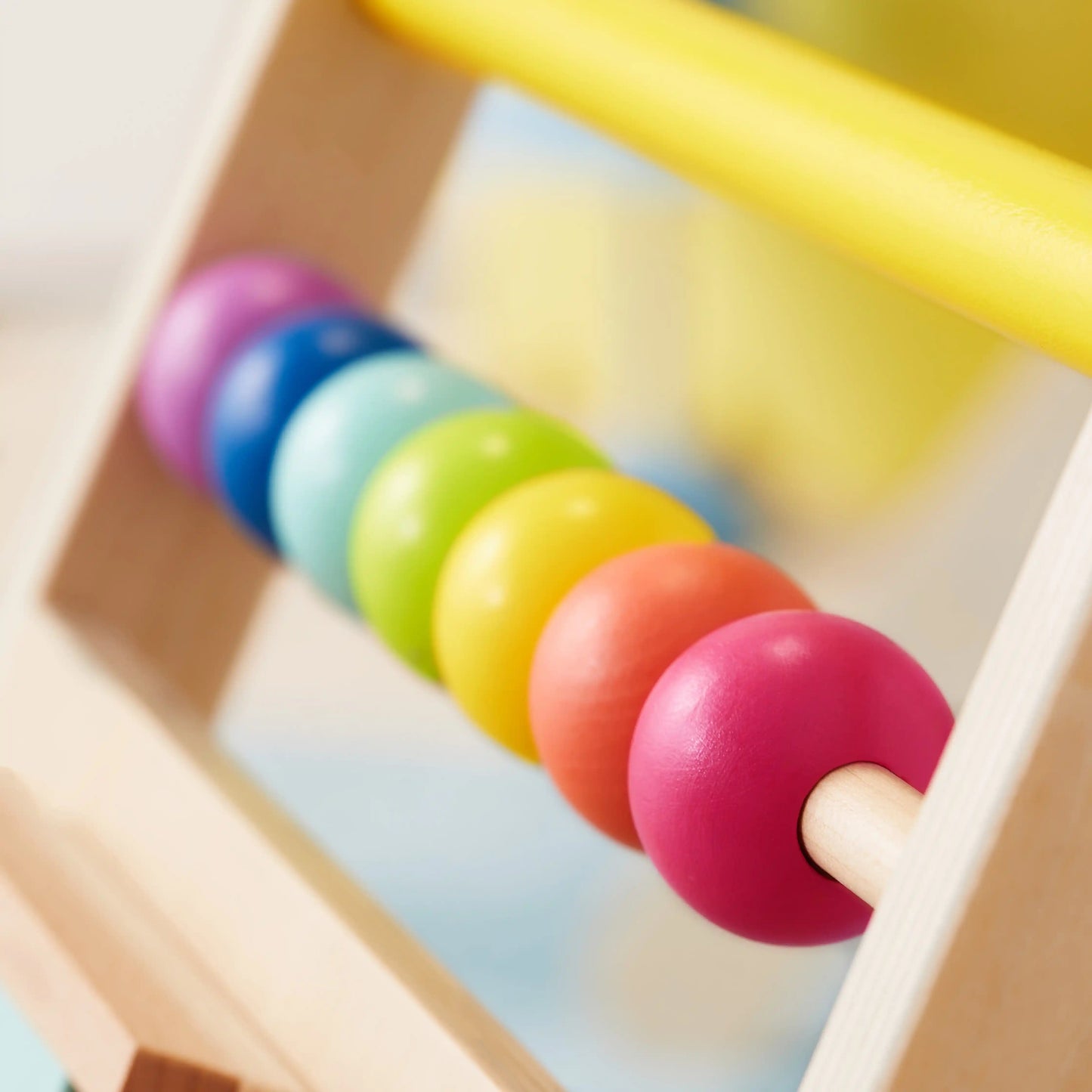 Close-up of a wooden abacus with colorful beads on a rod, featured as part of the Tiny Land® Premium Natural Wooden Activity Walker. The softly blurred background highlights its design.