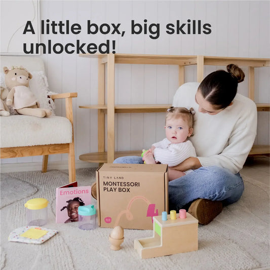 A woman sits on the floor with a baby next to a Tiny Land® Montessori Toys for Infants (10–12 Months) box filled with wooden toys and a book titled Emotions. Text above reads, "A little box, big skills unlocked!" in a cozy, light-filled room.