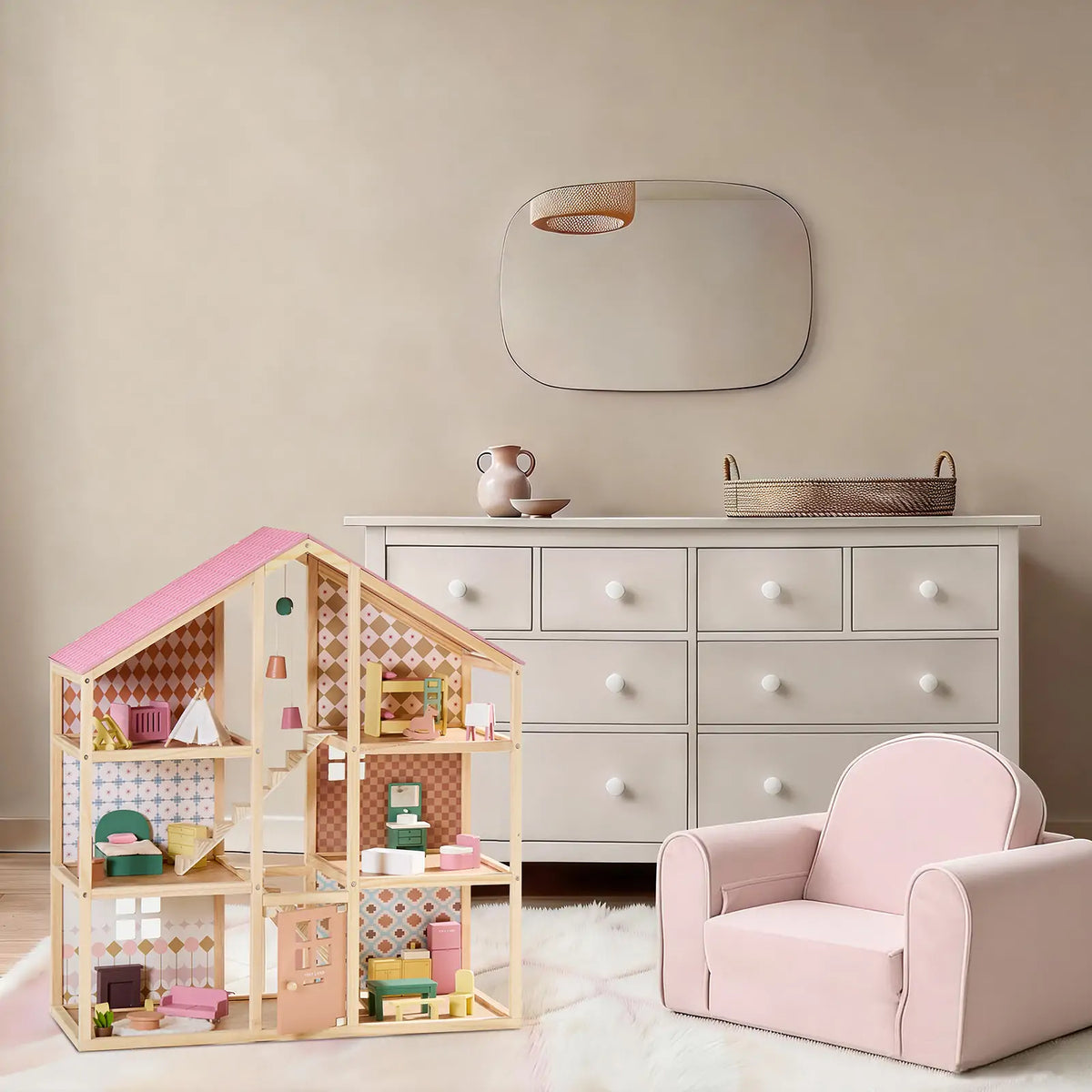 A multi-story Pegasus Wooden Dollhouse with Poseable Dolls, featuring a pink-and-grey roof, is furnished with miniature pieces and sits next to a small pink armchair on a white rug.