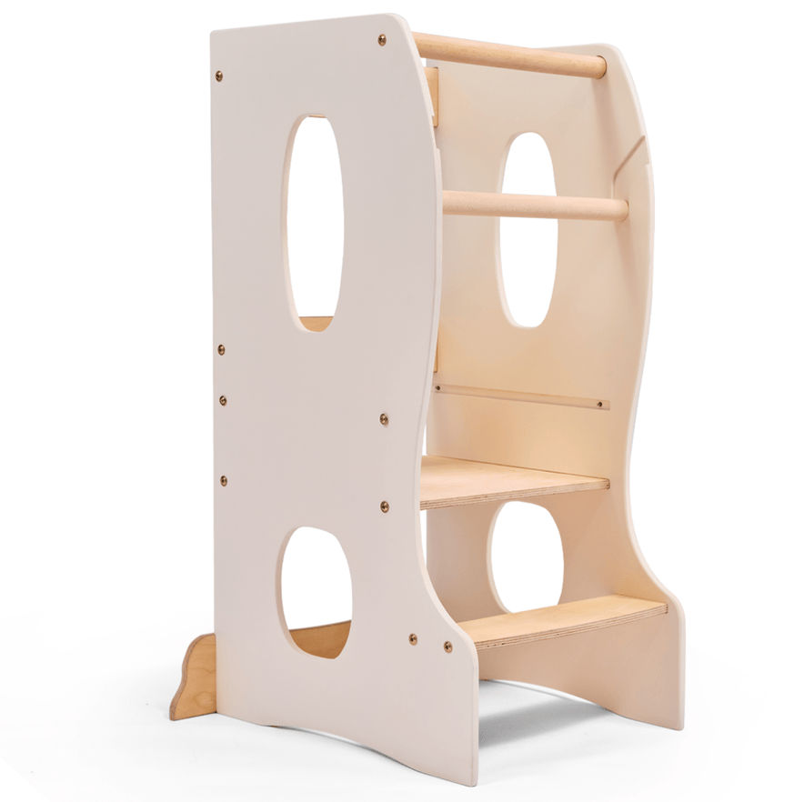 The Stable Montessori Learning Tower: Wooden Growing Chair - Ivory features natural wood, an adjustable platform, two steps, side cut-out handles, and safety rails. Its light ivory design lets kids safely reach higher surfaces while building independence.