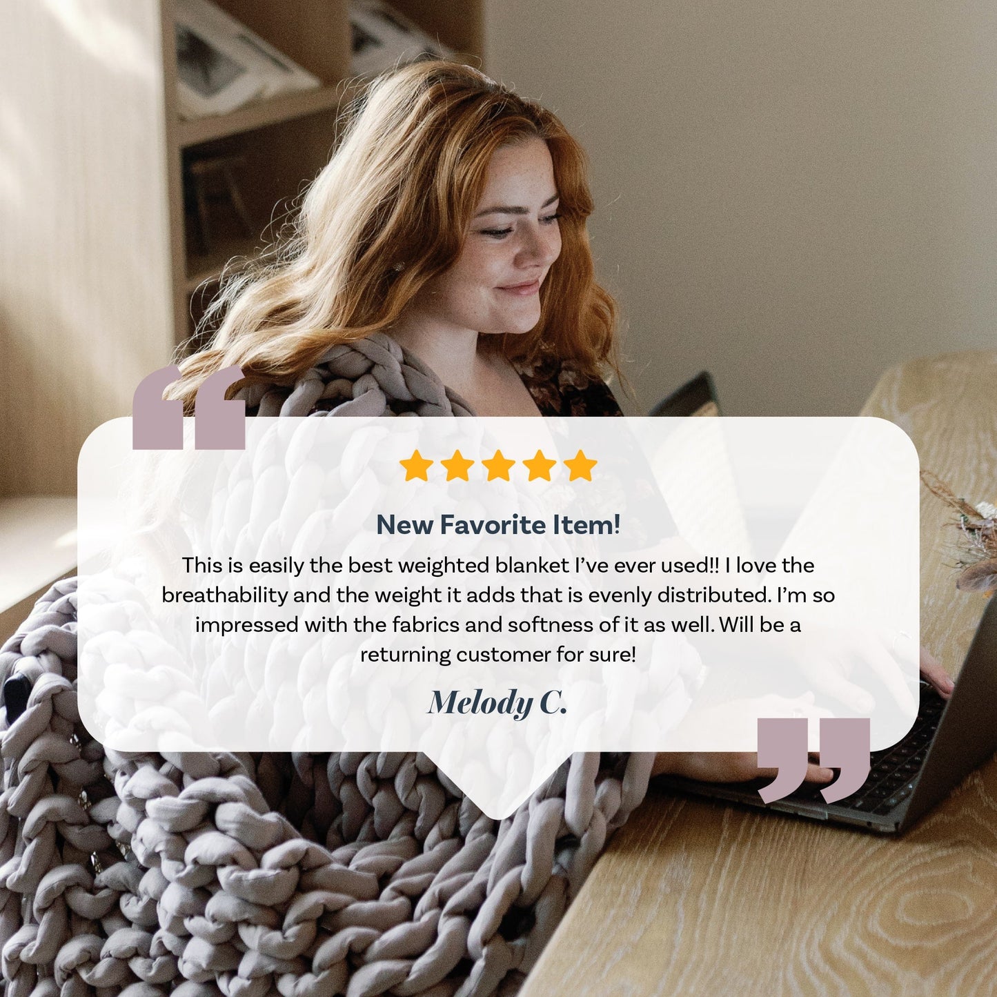 A woman with long red hair smiles at a table, wrapped in a super soft Knit Weighted Blanket while using her laptop. A five-star customer review appears in front of her.