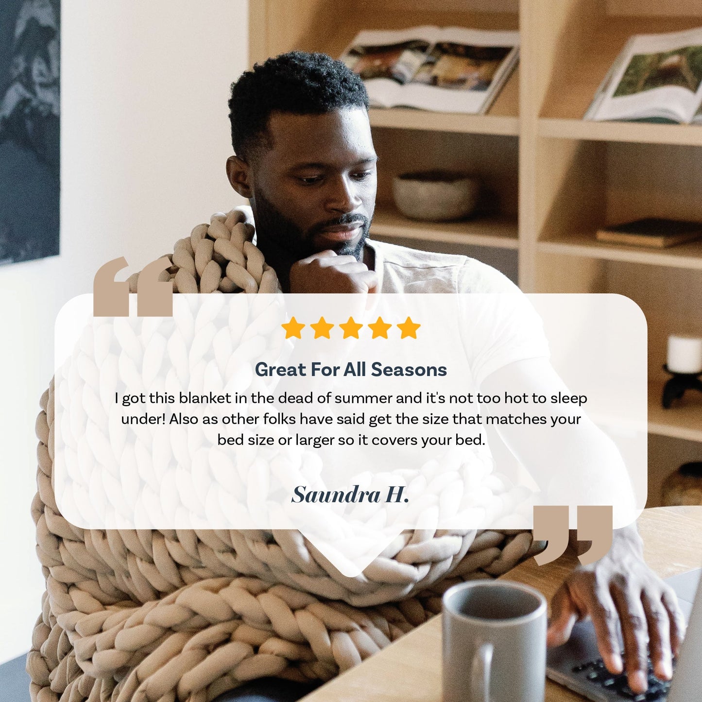 A man sits at a table with a laptop, wrapped in a Knit Weighted Blanket. A five-star review praises its comfort in every season and suggests choosing the right size. A coffee mug and plant complete the cozy scene.