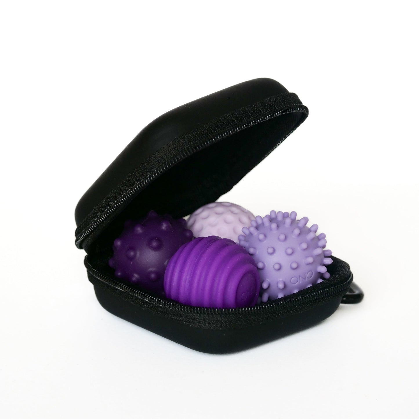 An open black zippered case holds three lavender Signets massage balls with spiked and ridged textures, designed to enhance your fidgeting experience and help improve focus.