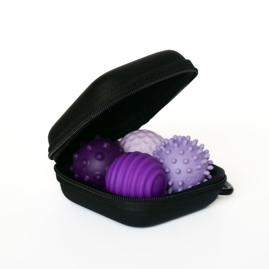 An open black zippered case holds three lavender Signets massage balls with spiked and ridged textures, designed to enhance your fidgeting experience and help improve focus.