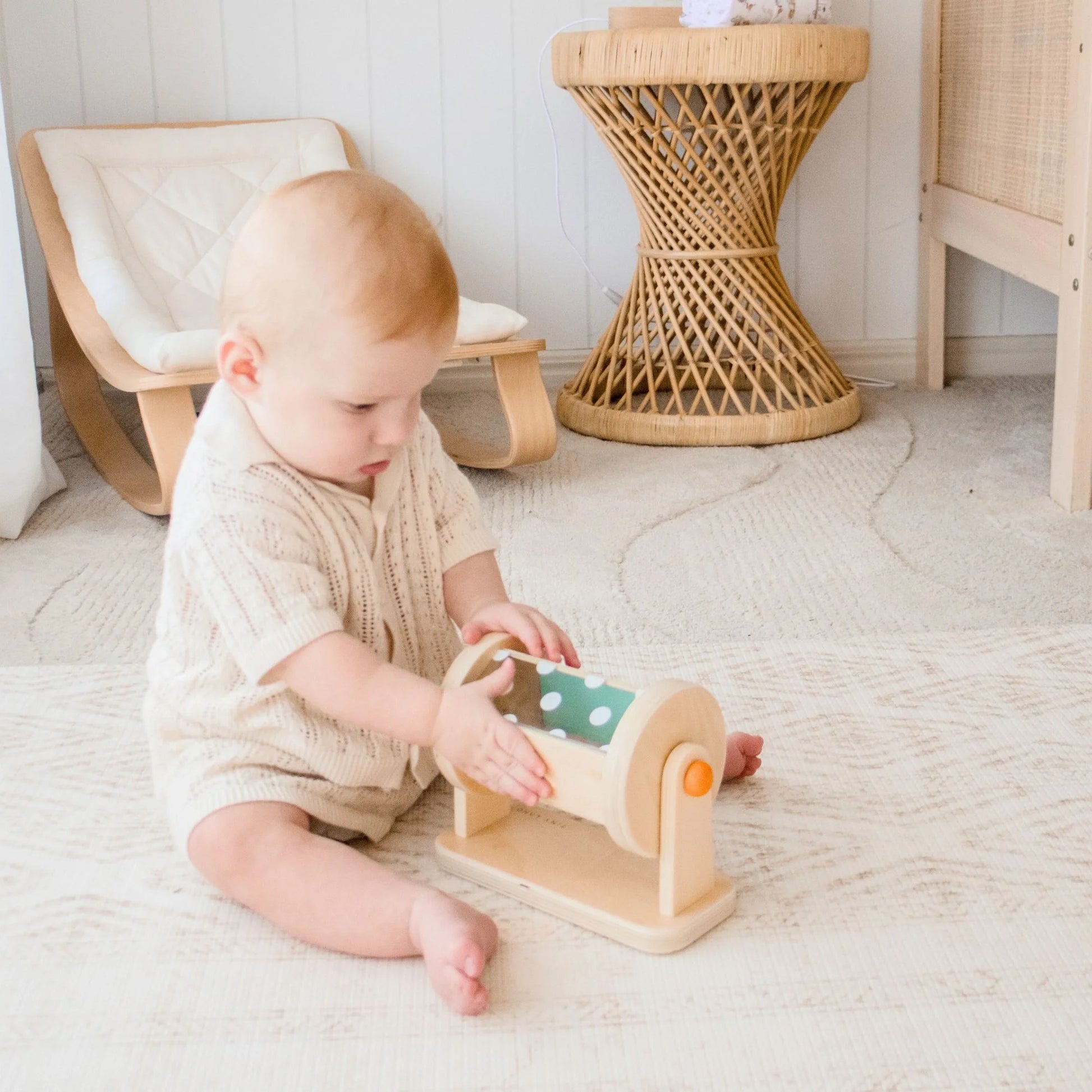A baby enjoys the Tiny Land® Montessori Toys for Newborns (4–6 Months) on a light rug, developing fine motor skills in a softly lit, minimalist nursery with neutral-toned furniture.