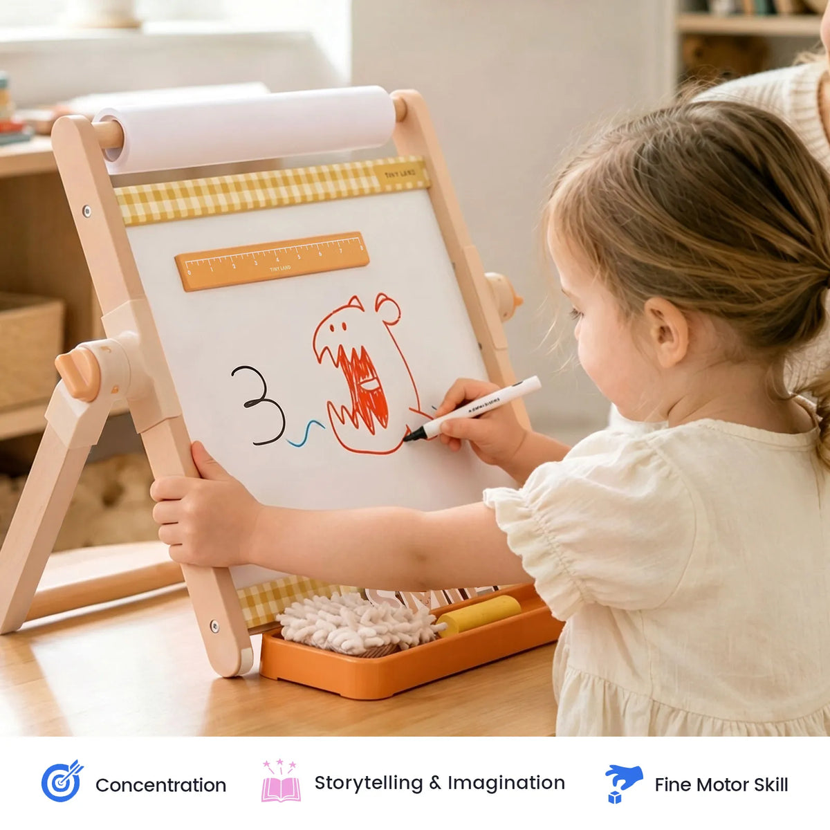 A child draws a monster on a 3-in-1 Adjustable Tabletop Art Easel that features an integrated ruler and a roll of paper.