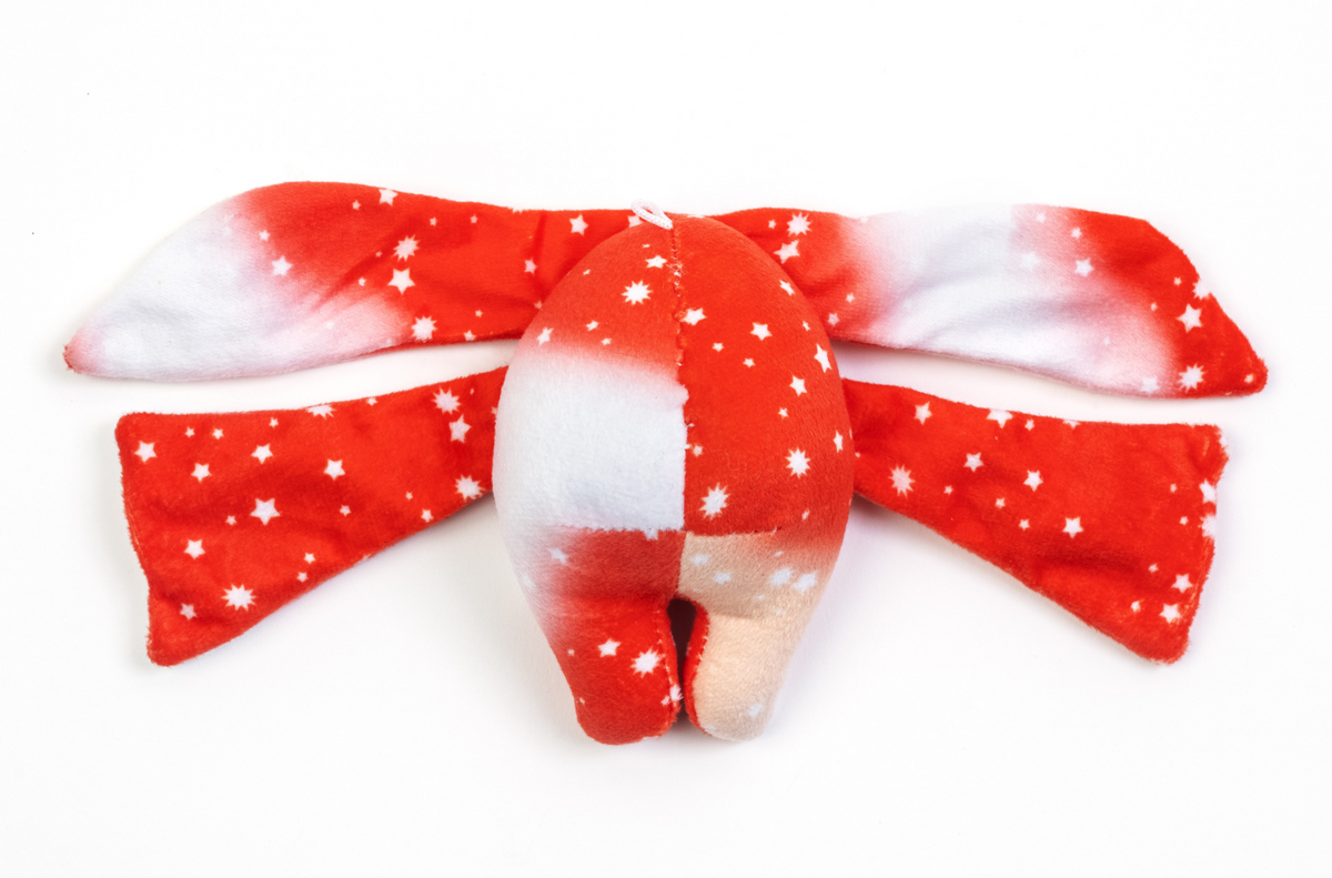 A Rover Mini Wrist Hugger – Magnetic Sensory Plush with a red and white star-patterned body and long, flat appendages extending from the sides.