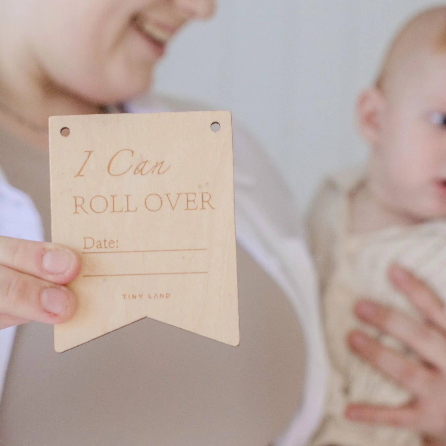 Celebrate milestones with a wooden "I Can Roll Over" sign (with space for a date) while holding your baby—perfect alongside Tiny Land® Montessori Toys for Newborns (4–6 Months) to encourage development.