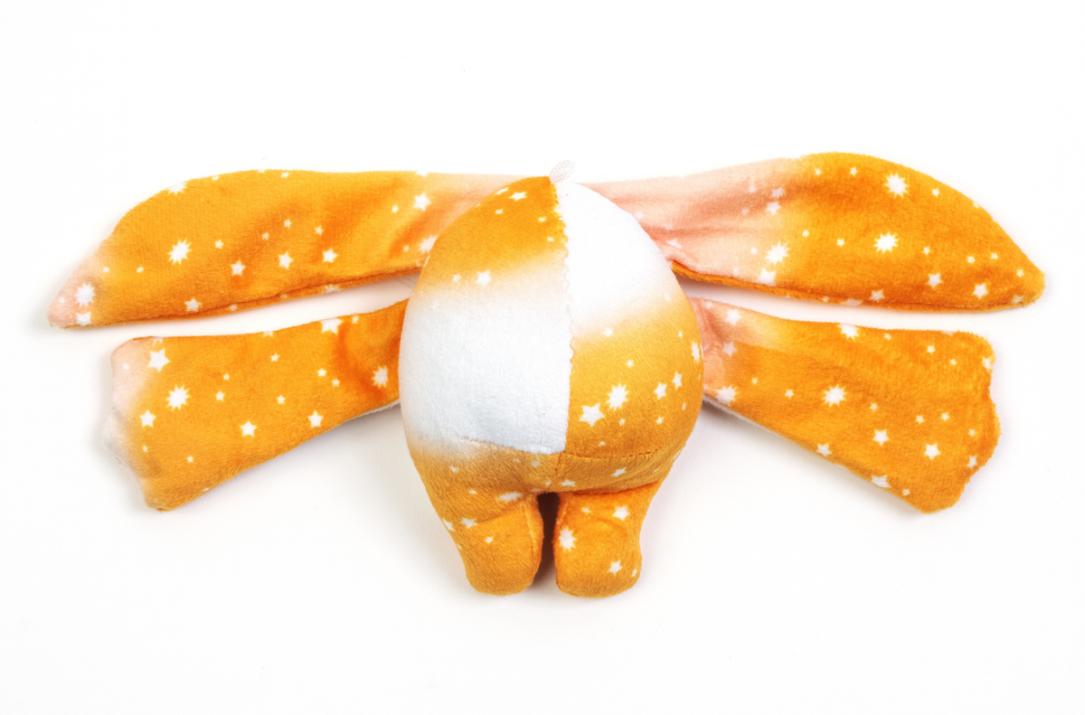An Ori Mini Wrist Hugger – Magnetic Sensory Plush with a plush, orange and white star-patterned body and two long, floppy ears extending to the sides.