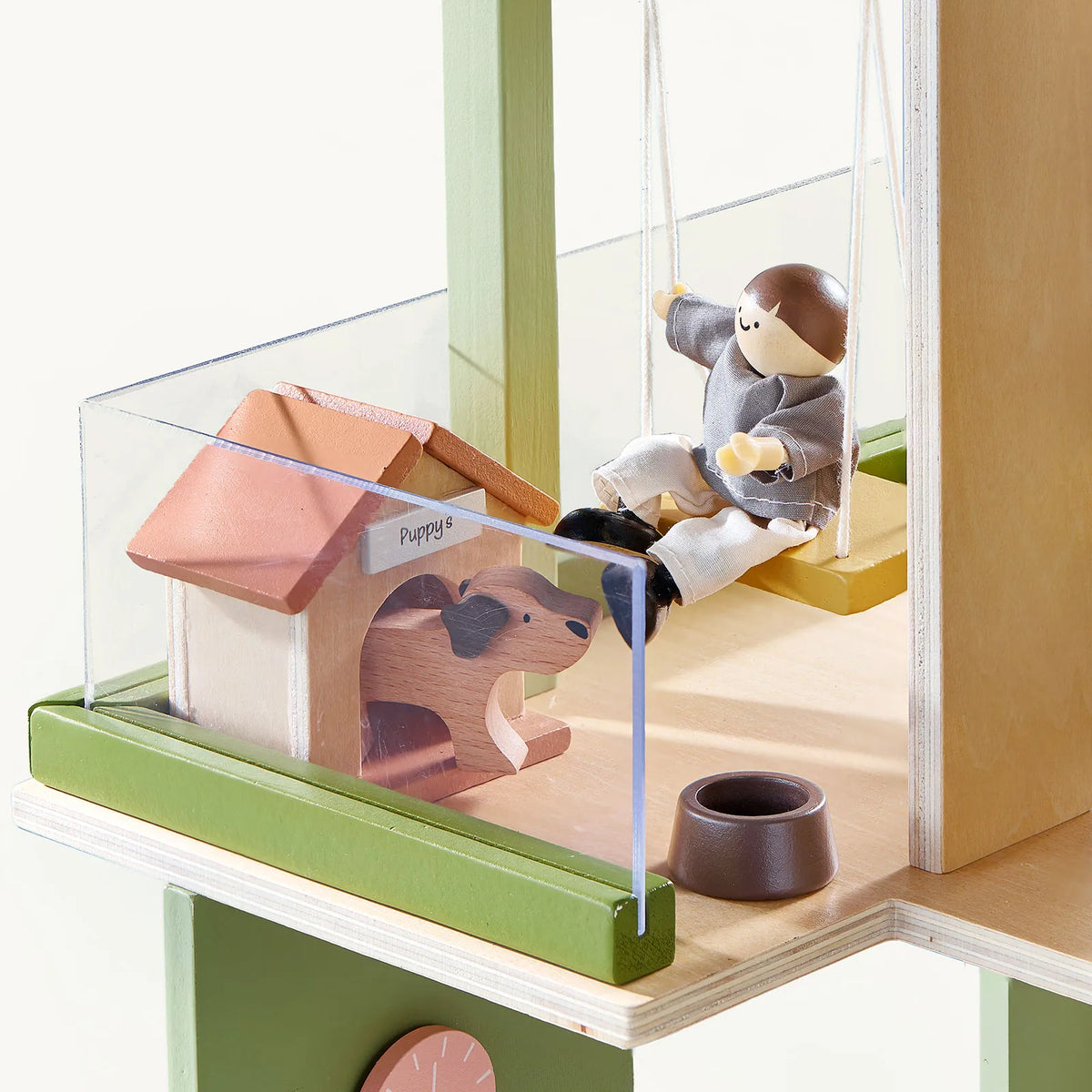 A 1:12 scale Sweetwood Cottage Dollhouse (48-pc Furniture) platform featuring a toy figure on a swing, a doghouse labeled Puppys with a dog inside, and a small bowl.